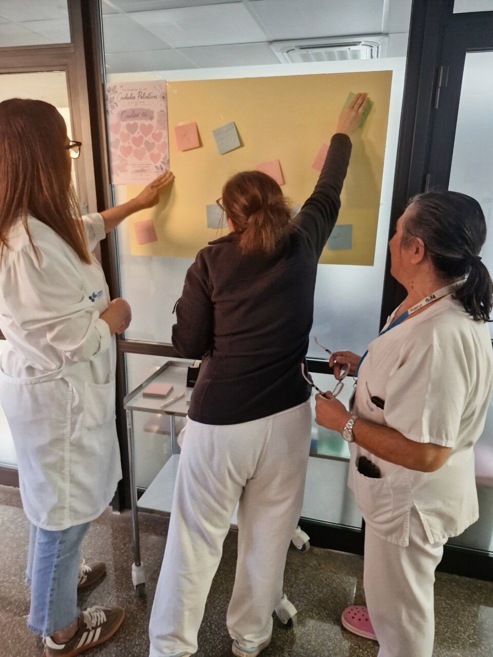 Trabajadores de cuidados paliativos escribiendo mensajes de apoyo en un mural