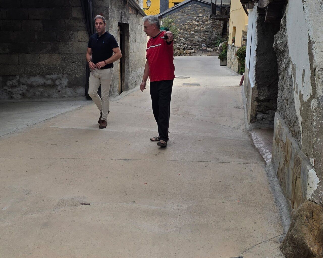 Dos hombres caminando por una calle renovada en Villanueva de Valdueza