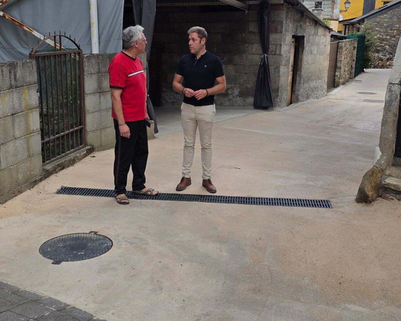 Dos hombres conversando en una calle renovada de Villanueva de Valdueza