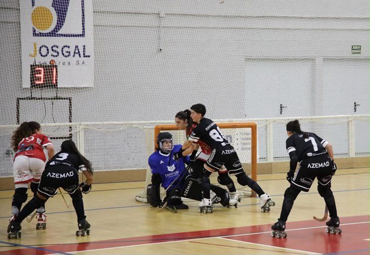 Jugadoras de hockey sobre patines disputan una acción frente a la portería durante un partido.