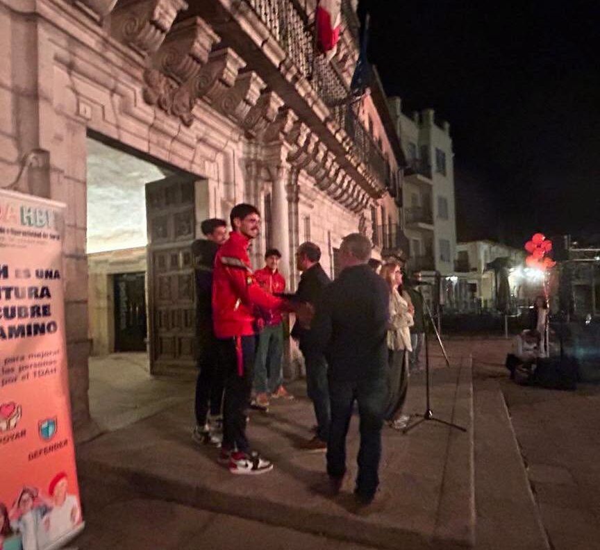 Grupo reunido de noche ante un edificio, junto a una pancarta sobre el TDAH.