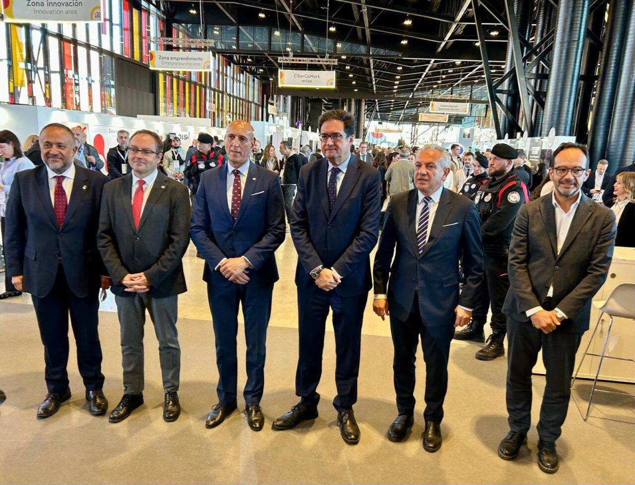 Grupo de asistentes posa en un recinto ferial con señalización de ENISE.