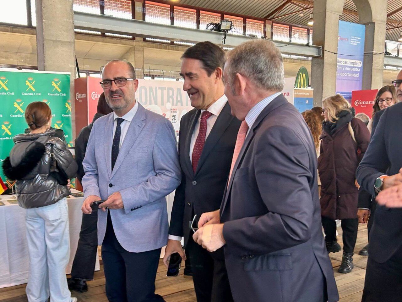 Varias personas conversan entre puestos informativos de una feria de empleo