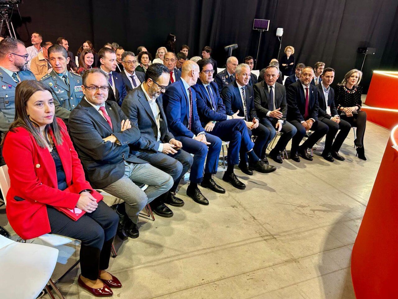 Personas sentadas en filas durante un acto en un espacio cubierto.