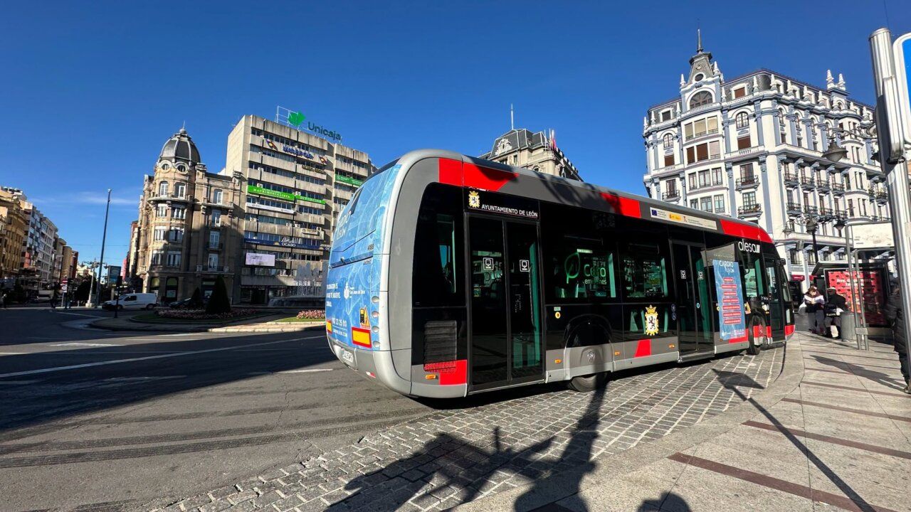 Autobús urbano de León en una avenida, frente a edificios históricos y modernos.