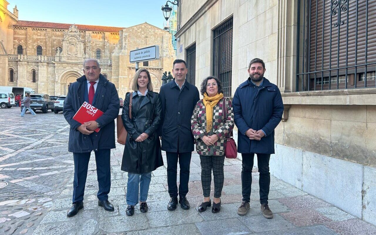 Cinco personas posan en una plaza empedrada junto a un edificio histórico.