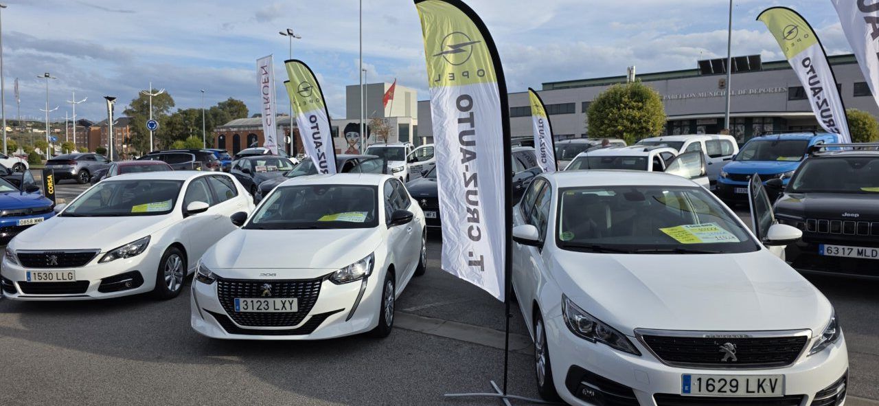Varios coches aparcados en un recinto con banderolas publicitarias de Opel.