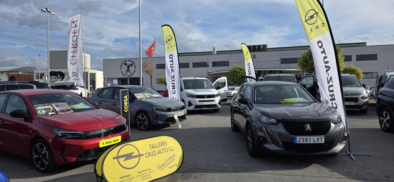 Varios coches expuestos al aire libre junto a banderas y carteles de Opel.