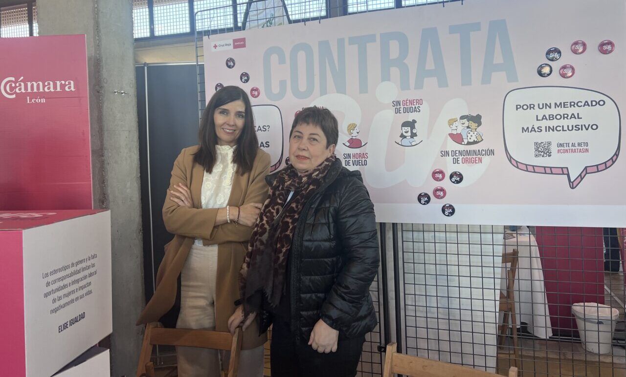 Dos mujeres posan ante un panel de la campaña Contrata Sin sobre empleo inclusivo.