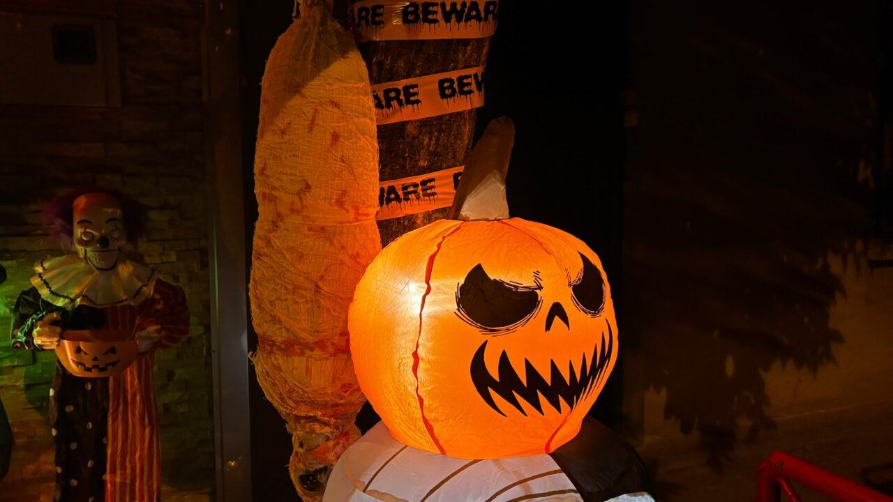 Decoración de Halloween con calabaza iluminada, figura de payaso y figura envuelta.