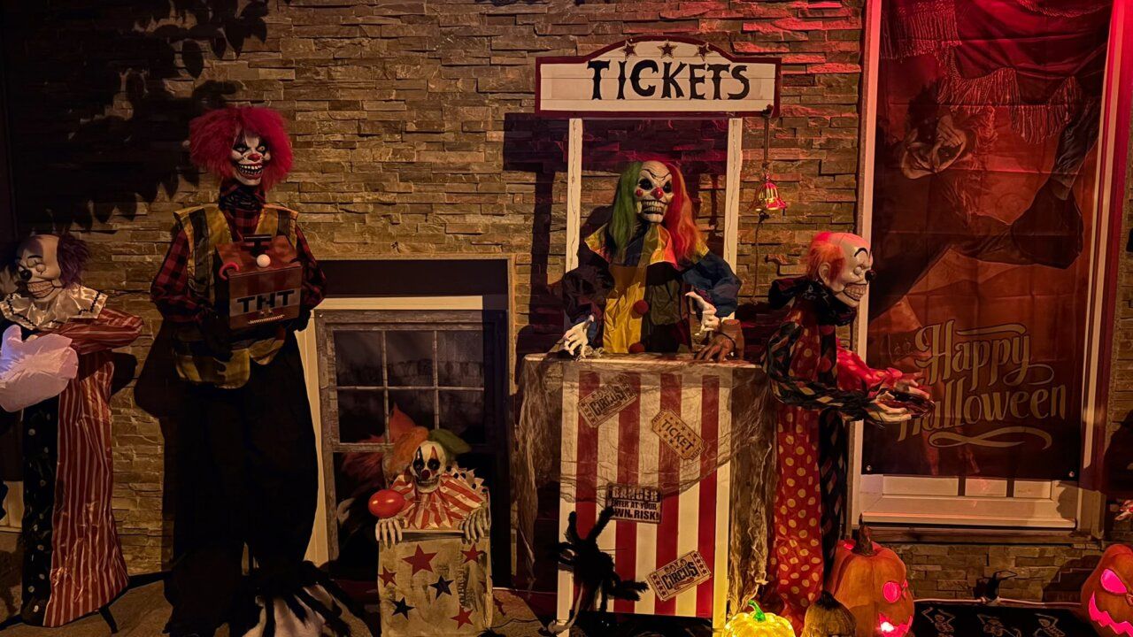 Escena decorativa de Halloween con payasos terroríficos, taquilla de tickets y calabazas.