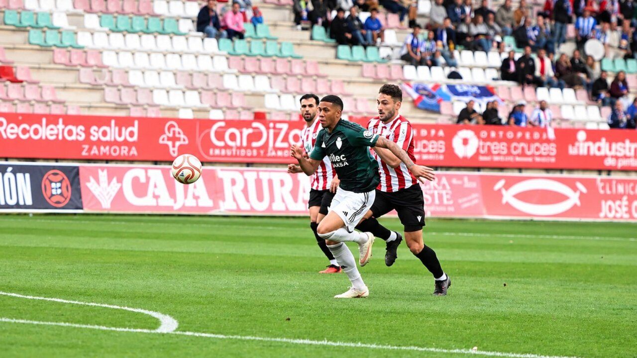 Tres futbolistas disputan un balón durante un partido en un campo de césped