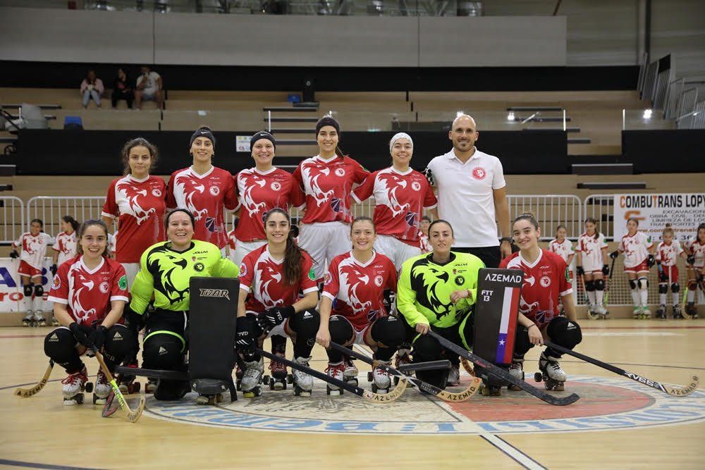 Jugadoras de hockey sobre patines posan en grupo en la pista con sus sticks.
