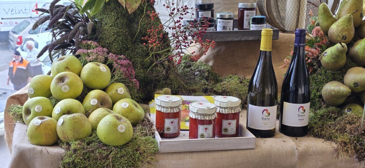 Expositor con peras, tarros de conservas y botellas de vino entre ramas decorativas.