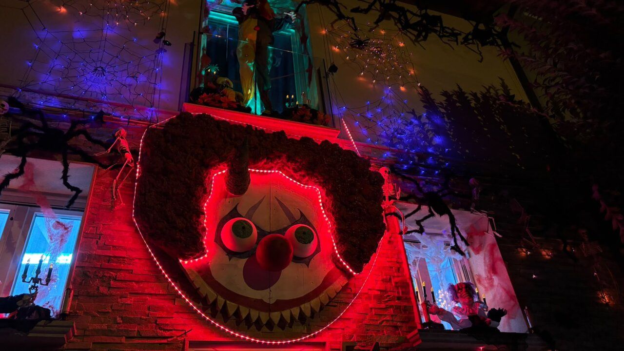 Fachada decorada para Halloween con un gran payaso iluminado y telarañas