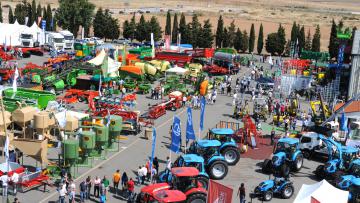 Vista panorámica de una feria agropecuaria con maquinaria agrícola y visitantes.