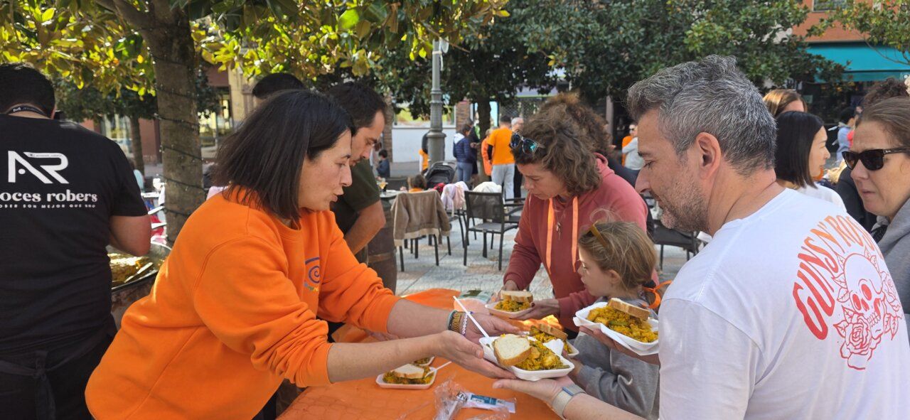 Varias personas sirven platos de comida durante una convivencia al aire libre.