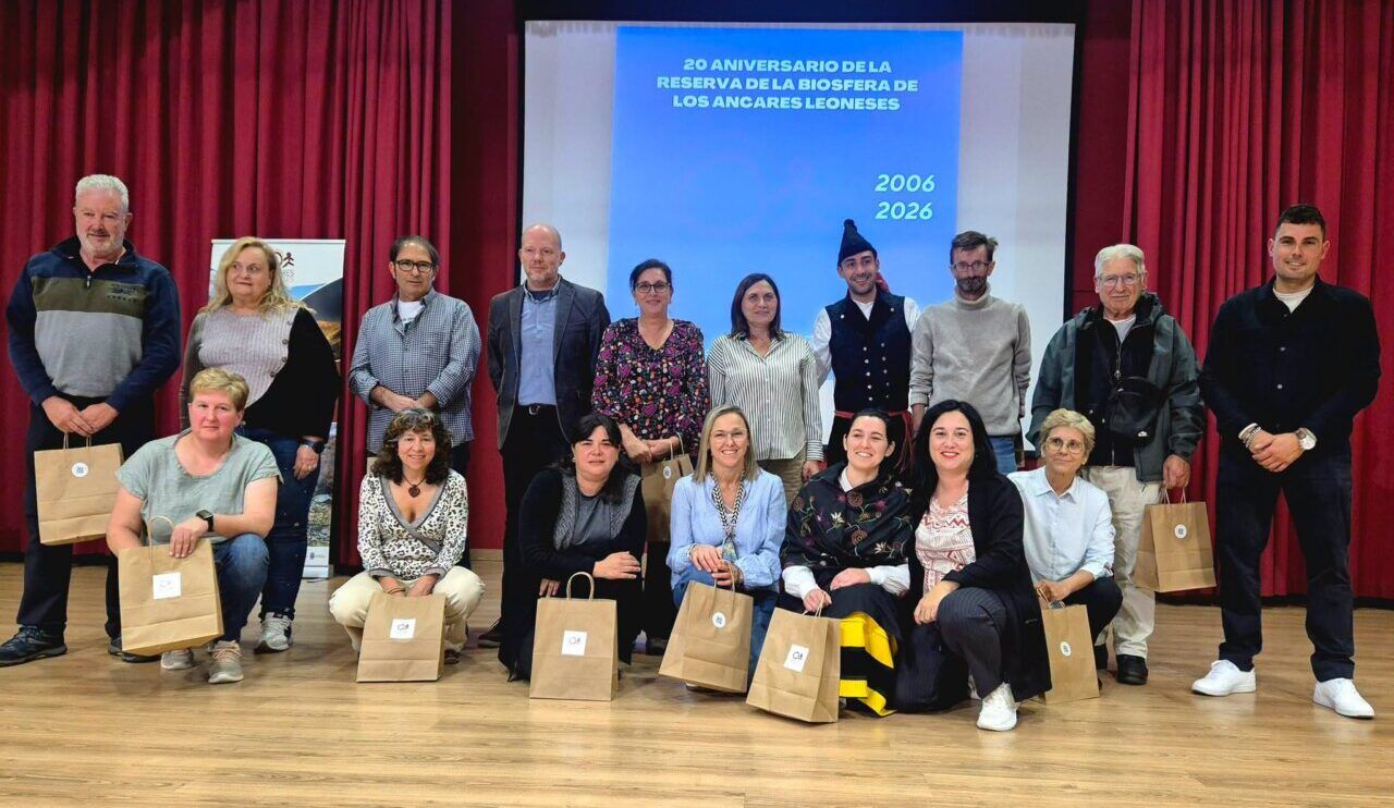 Grupo de personas posa frente a una pantalla del 20 aniversario de los Ancares Leoneses.