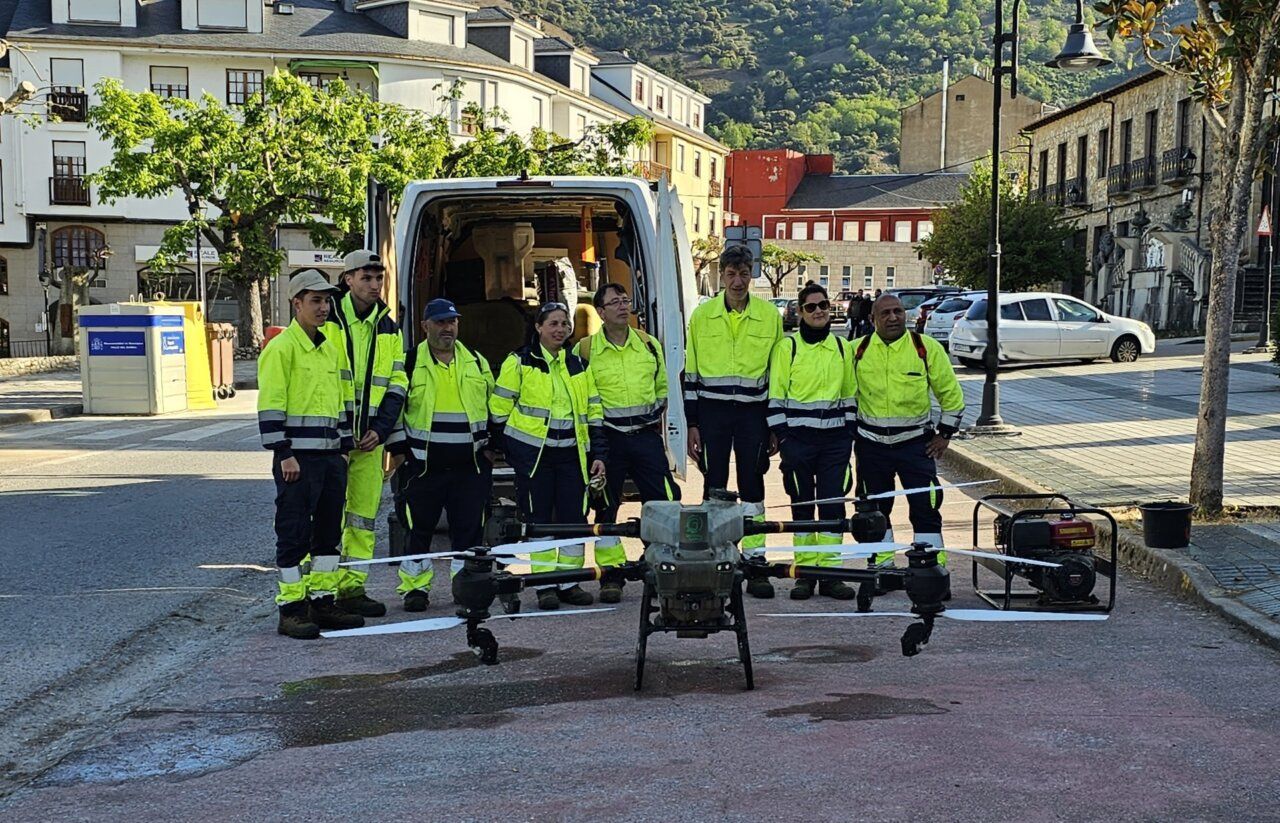 Personas con ropa reflectante junto a un dron de gran tamaño en una calle