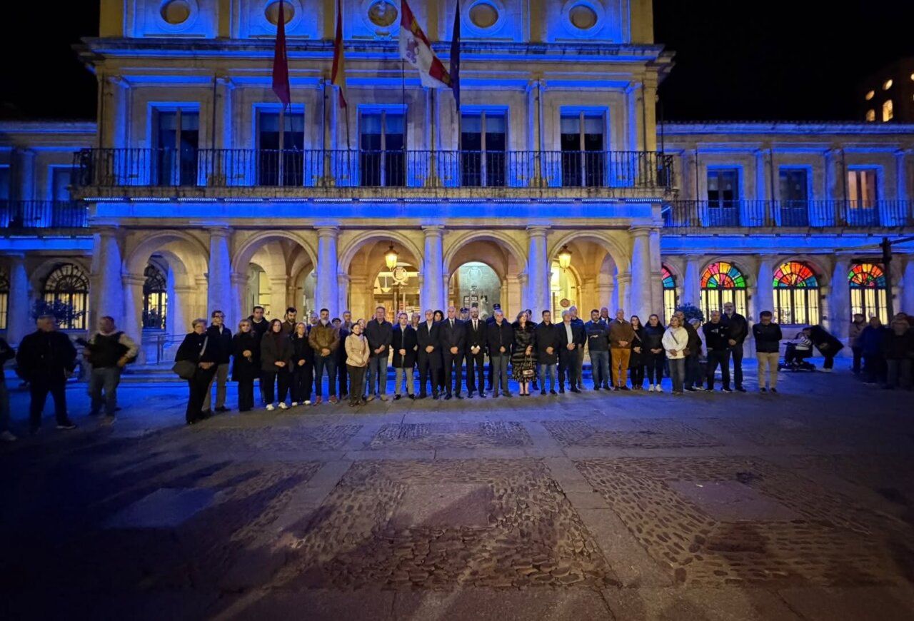 Grupo de personas frente a un edificio iluminado de azul durante la noche
