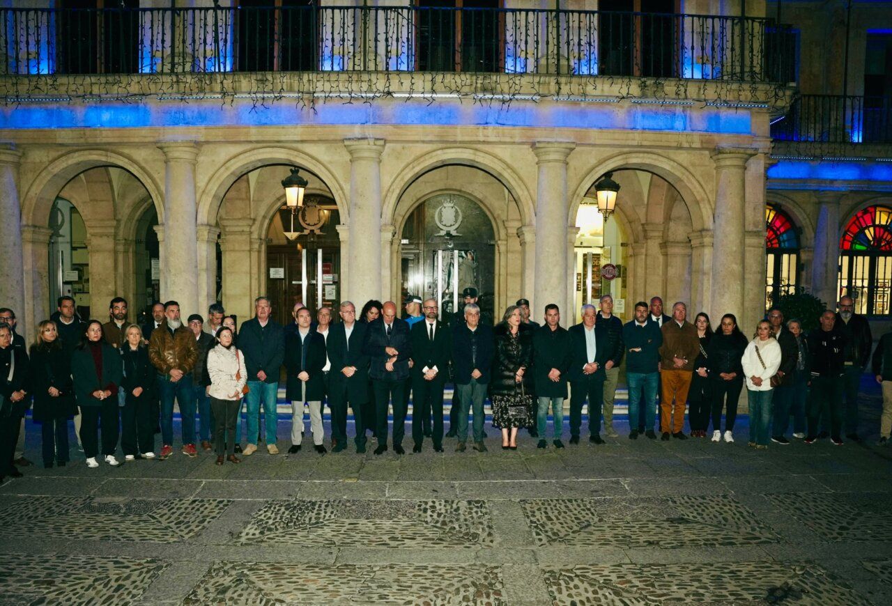 Grupo de personas reunido frente a un edificio con soportales iluminado de noche