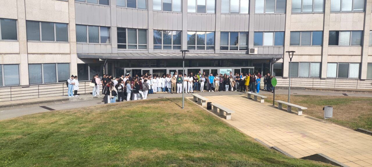 Grupo de personas reunido frente a la entrada de un edificio de varias plantas.