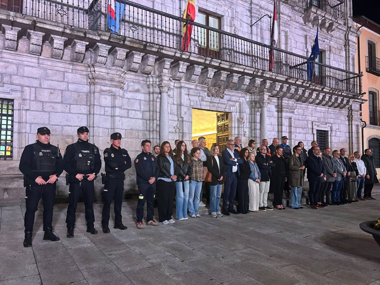Grupo de personas, incluidos agentes uniformados, reunido frente a un edificio de piedra.
