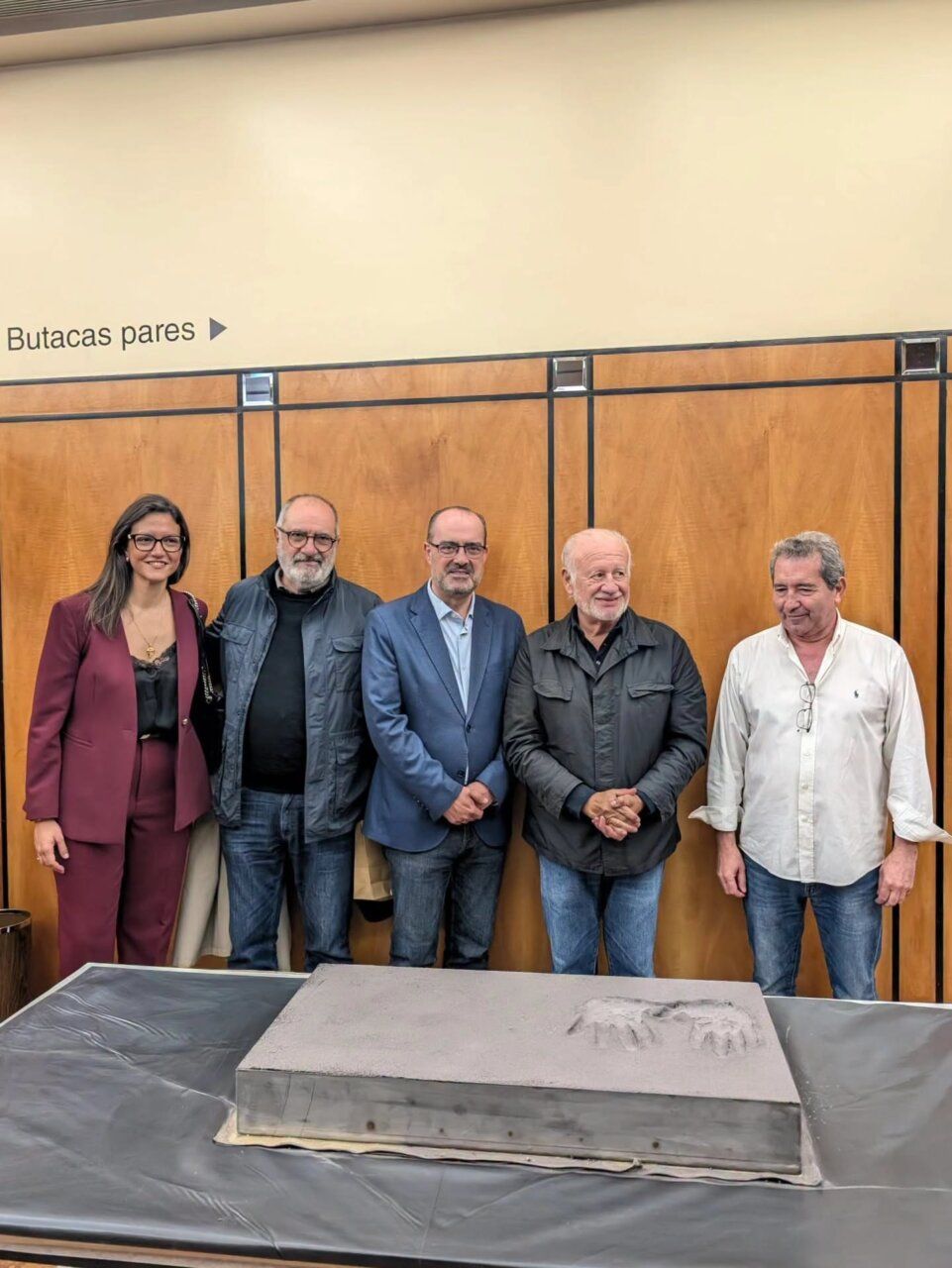 Cinco personas posan detrás de una placa con huellas en relieve.