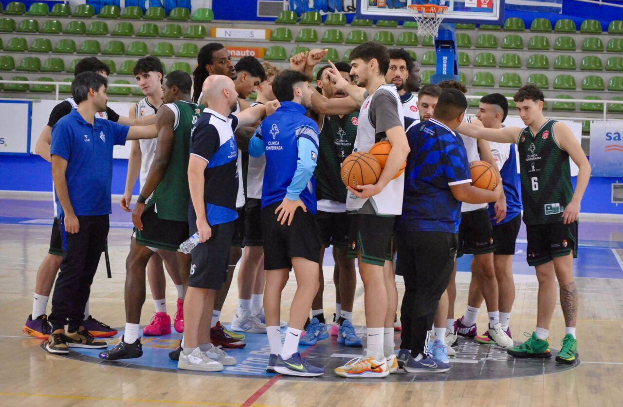 Jugadores de baloncesto se reúnen en círculo en una pista cubierta, algunos con balones.