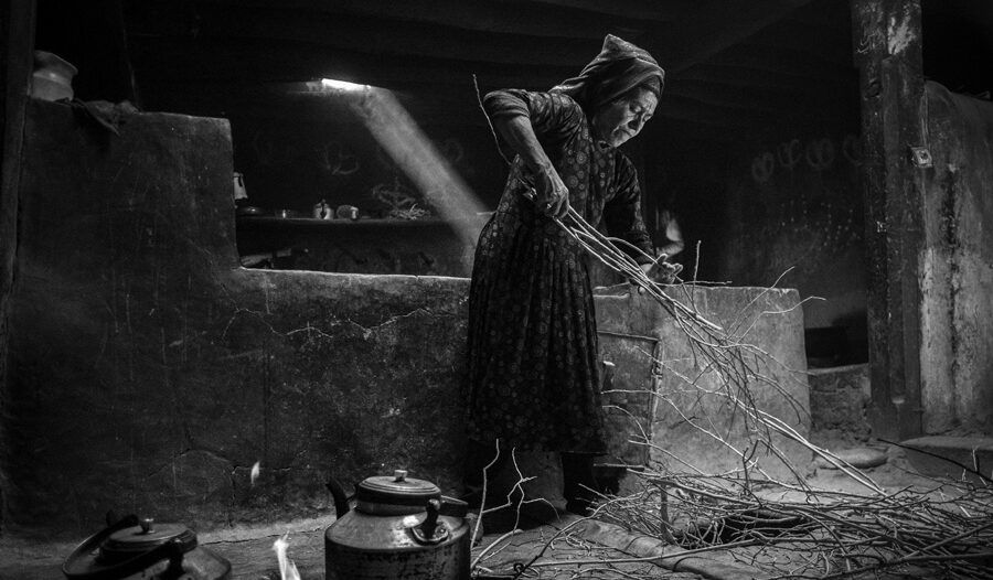 Mujer trabajando en un entorno rural con ramas y utensilios de cocina