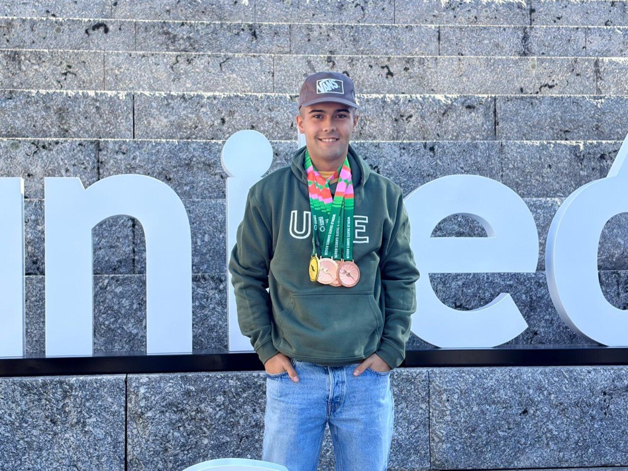 Joven con sudadera de la ULE posa con tres medallas colgadas al cuello.