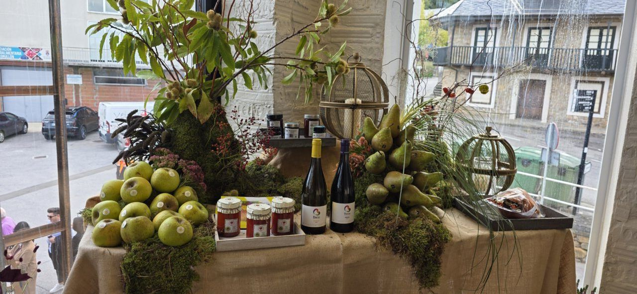 Mesa decorada con frutas verdes, tarros de conservas y dos botellas de vino.