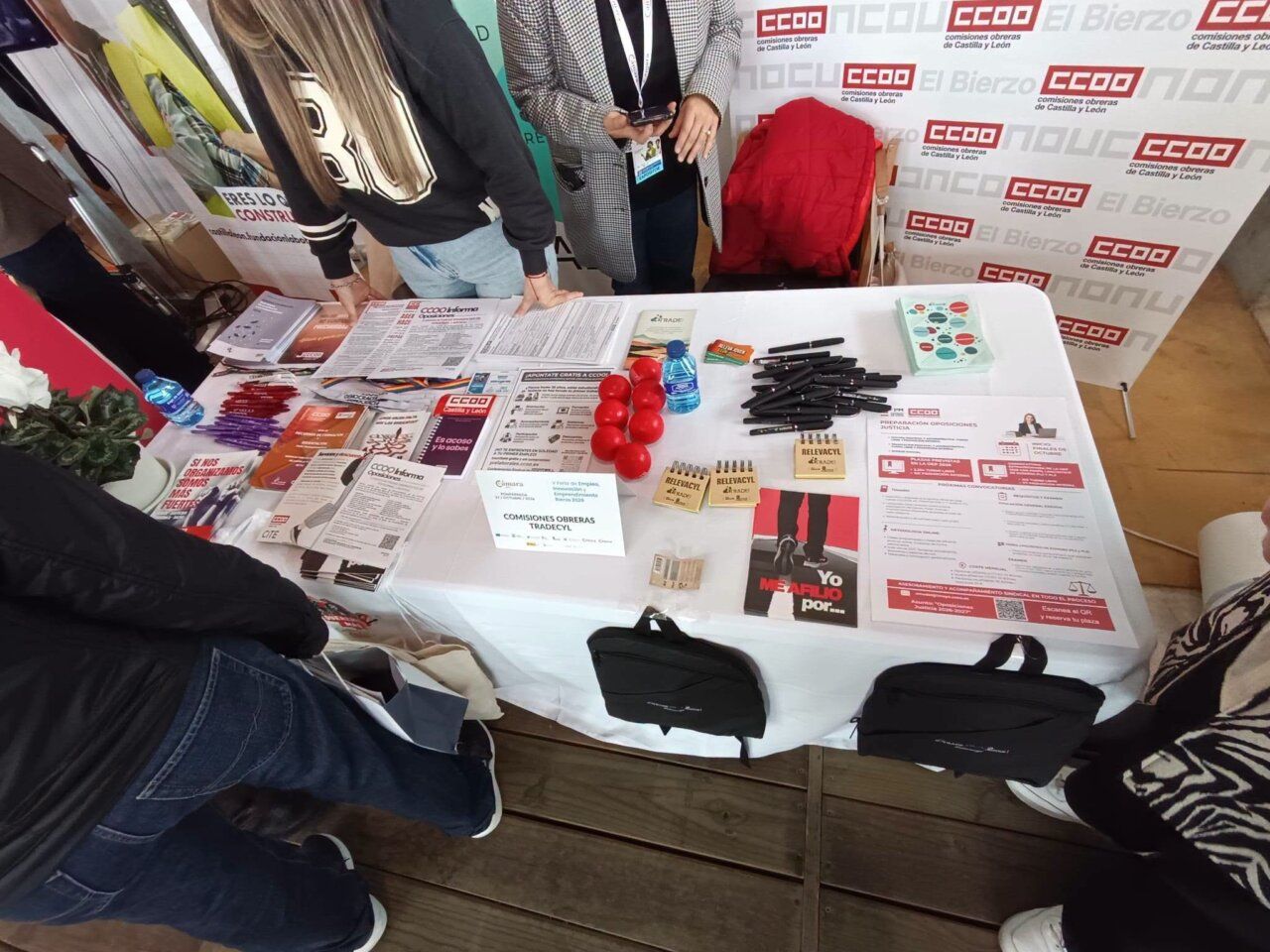 Mesa con folletos, bolígrafos y globos rojos ante un panel de CCOO.