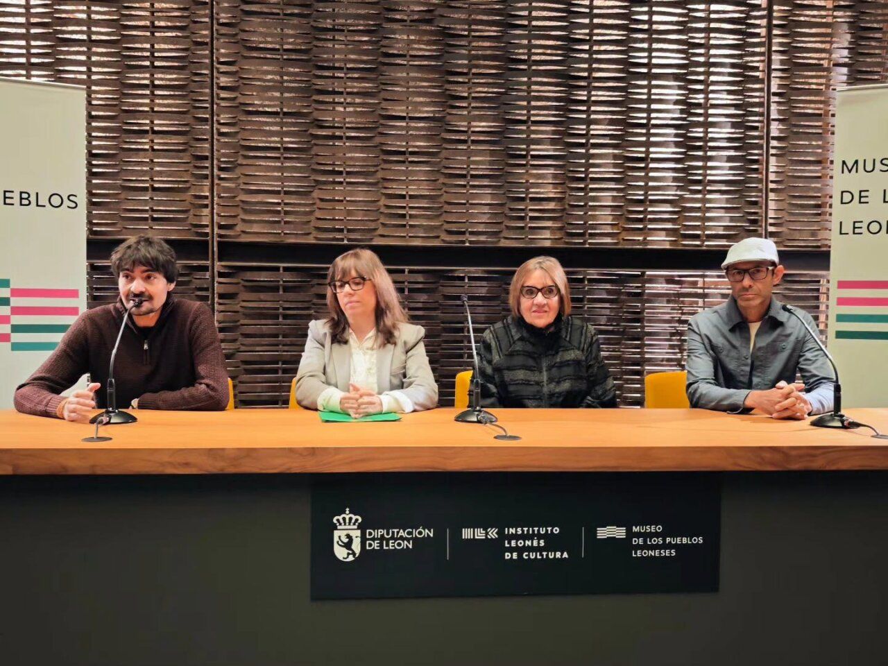 Cuatro personas sentadas tras una mesa con micrófonos en una sala del museo.
