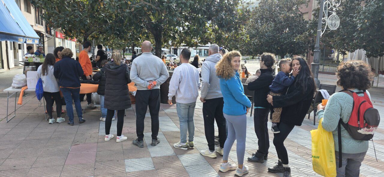 Personas reunidas junto a unas mesas en una plaza peatonal de Ponferrada.