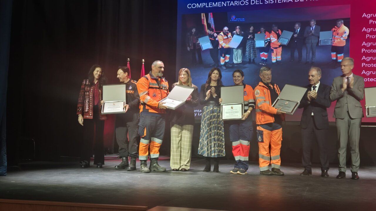 Varias personas sostienen certificados en un escenario durante una ceremonia pública.