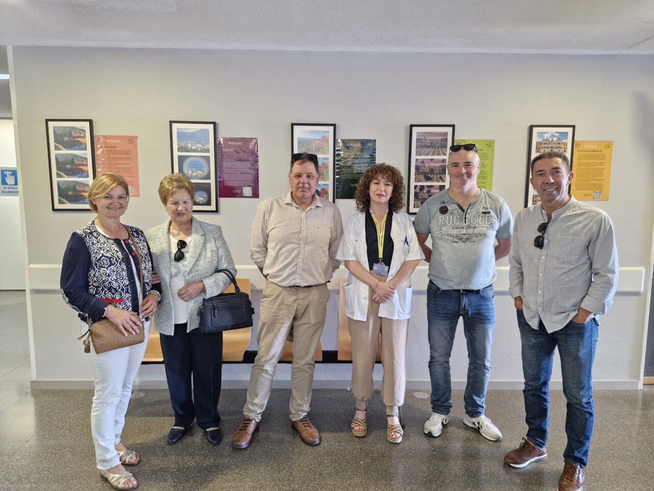 Seis personas posan frente a paneles y fotografías de la exposición Miradas.
