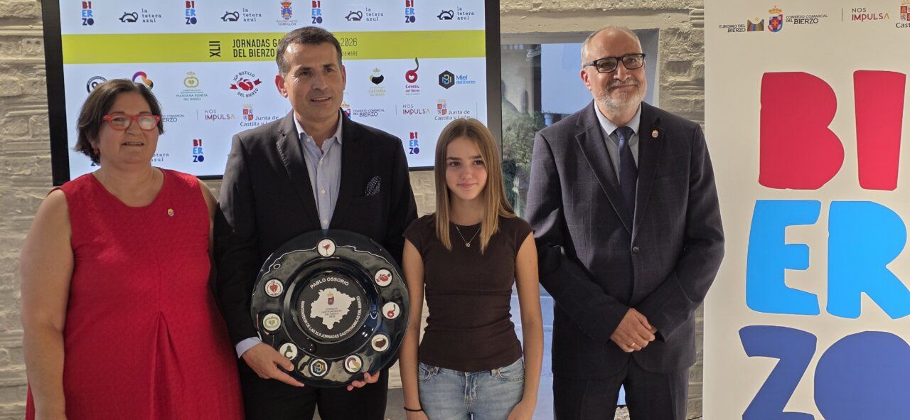 Cuatro personas posan durante las Jornadas Gastronómicas del Bierzo junto a una placa conmemorativa.