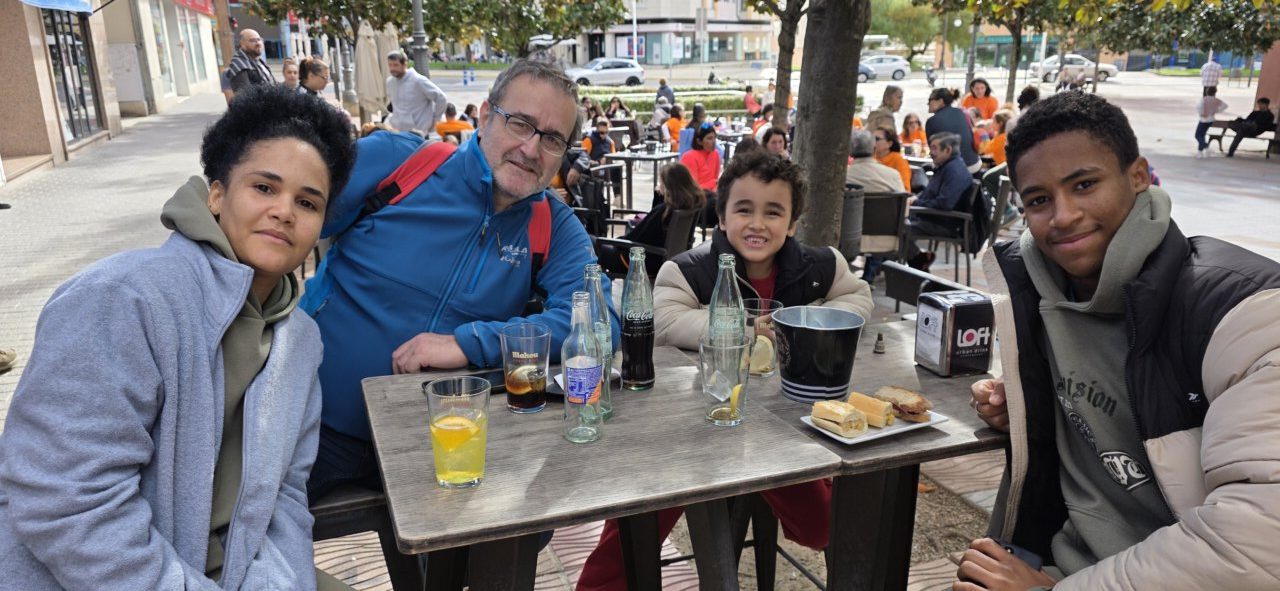Varias personas sentadas alrededor de una mesa con bebidas y comida en una terraza.