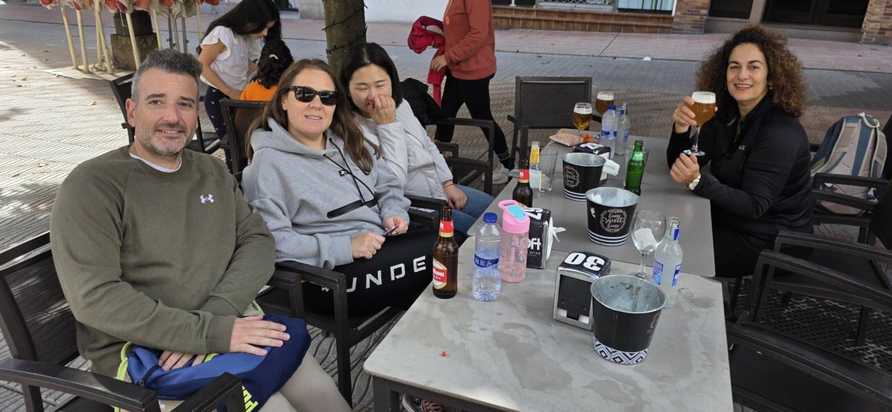 Varias personas sentadas alrededor de una mesa exterior con bebidas y botellas.