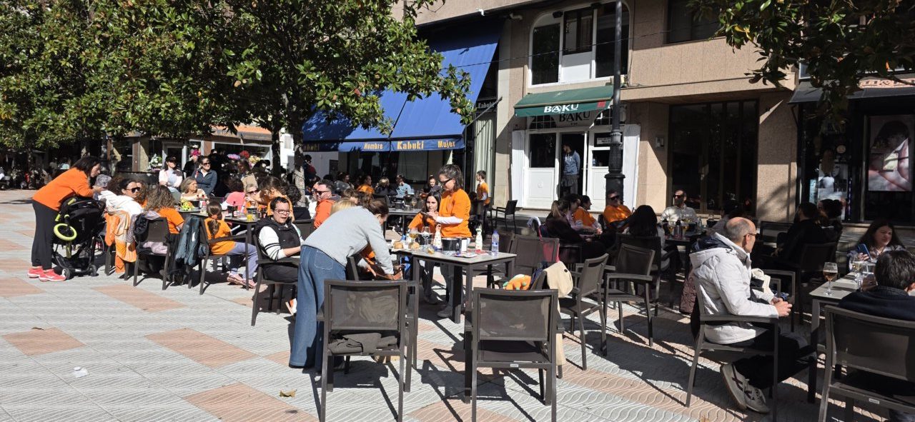 Personas sentadas alrededor de mesas al aire libre en una plaza peatonal