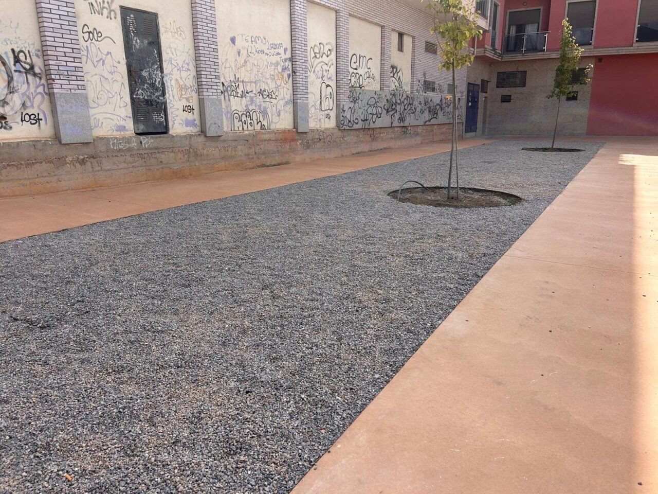 Vista de la plaza de Cuatrovientos con gravilla y árboles.
