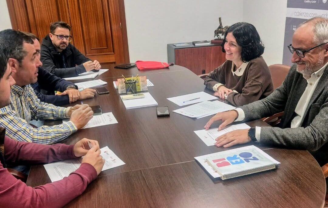 Varias personas sentadas alrededor de una mesa con documentos durante una reunión.