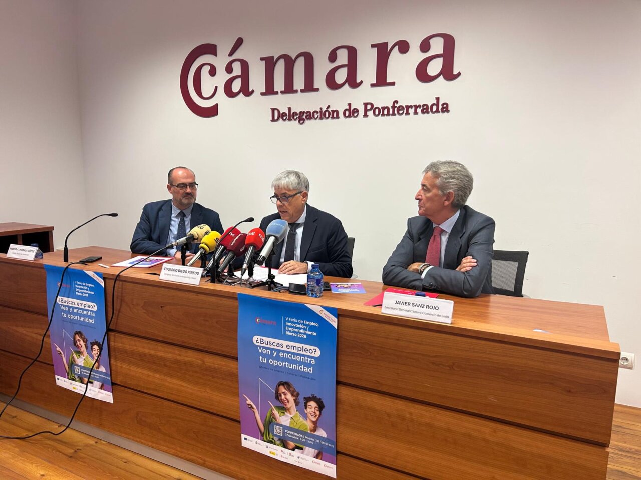 Tres hombres sentados en una mesa durante una rueda de prensa de la feria de empleo.