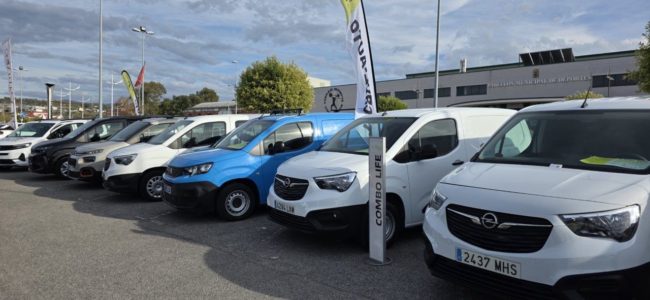 Varios vehículos Opel, incluidos furgones blancos y uno azul, alineados en un aparcamiento.