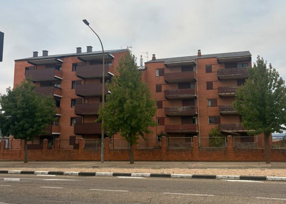 Edificio de viviendas camineros en Astorga con árboles y calle